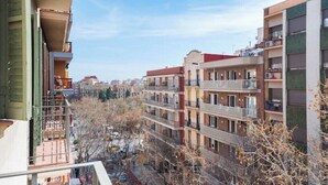Un edificio residencial de varios pisos con balcones, cielo despejado y árboles sin hojas.