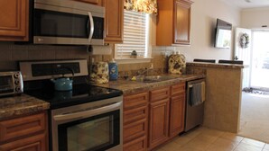 A kitchen with wooden cabinets, a microwave, an oven, a sink, and a countertop with a kettle. - Beach side vacation house (Myrtle Beach)