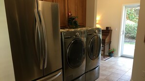 A kitchen with a stainless steel refrigerator and a double washer and dryer. - Beach side vacation house (Myrtle Beach)