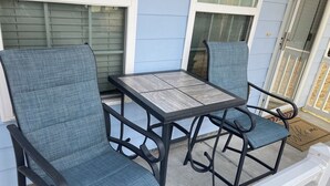 A patio with two blue cushioned chairs and a wooden table. - Beach side vacation house (Myrtle Beach)
