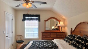 A bedroom with a bed, a dresser, a chair, a ceiling fan, a window with blinds, and a mirror. - Beach side vacation house (Myrtle Beach)