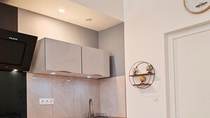 A modern kitchen with a built-in oven, a microwave, and a sink. There is a wooden countertop and light-colored cabinets. A globe and a clock are mounted on the wall. - Chill and Work  (Villeneuve-sur-Lot)