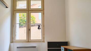 Een kamer met raam, radiator en een houten bureau met lades.