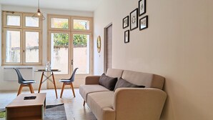 A living room with a beige sofa, two chairs, a small table, and a hanging light fixture. - Chill and Work  (Villeneuve-sur-Lot)