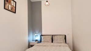 A bedroom with a bed, a nightstand, a wall-mounted light, and a framed photo on the wall. - Chill and Work  (Villeneuve-sur-Lot)