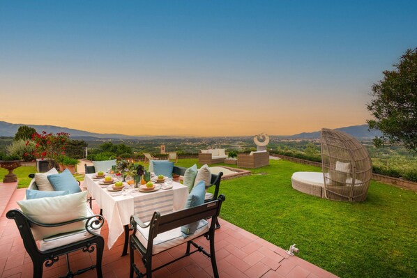 Une terrasse avec une table dressée pour les repas, du mobilier d’extérieur et une vue sur le paysage.