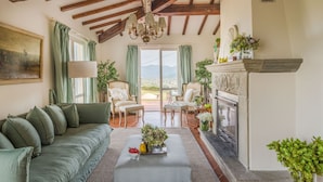 A spacious living room with a high ceiling, a fireplace, and a view of the mountains. - Villa Lontana in Lucca (Lucca)