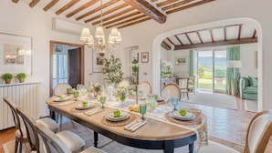 A dining area with a wooden table set for four, surrounded by chairs. - Villa Lontana in Lucca (Lucca)