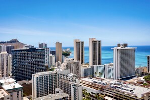 A high-rise hotel with multiple floors, a parking area, and a view of the ocean.