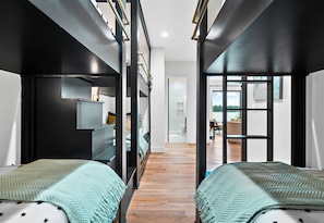 Two single beds with matching blankets, a wardrobe, and a seating area with a table and chairs.