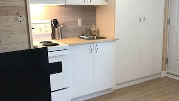 Een magnetron, een broodrooster, kookgerei, borden en bestek, eettafels