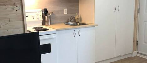 Een magnetron, een broodrooster, kookgerei, borden en bestek, eettafels