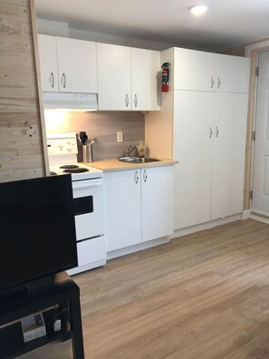 Een magnetron, een broodrooster, kookgerei, borden en bestek, eettafels