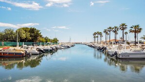 Una marina con imbarcazioni ormeggiate lungo una tranquilla via d'acqua, circondata da palme e un cielo sereno.