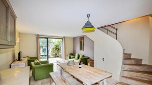 Un'ampia zona giorno con un tavolo da pranzo in legno, divani verdi e una scala che conduce a un piano superiore.