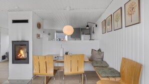 Un salon moderne avec une cheminée, des meubles en bois et des œuvres d’art encadrées accrochées aux murs.