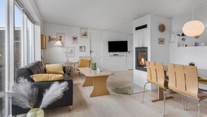Un salon moderne comprenant un canapé, une table à manger, des chaises et une cheminée.