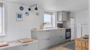 Une cuisine moderne avec des meubles blancs, un four encastré et une fenêtre offrant une belle vue.