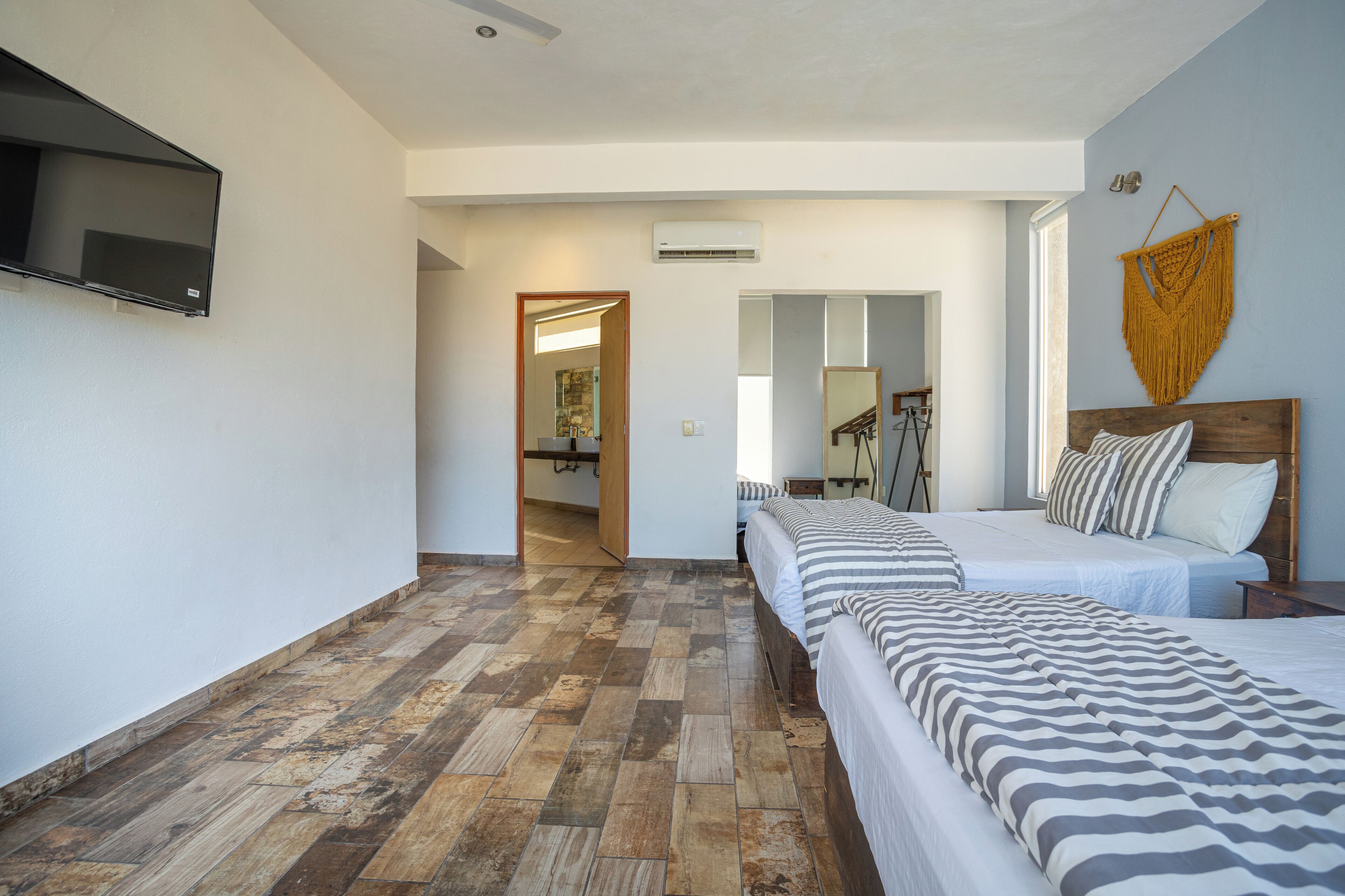 Een hotelkamer met twee bedden, een aan de muur bevestigde televisie en een houten vloer.