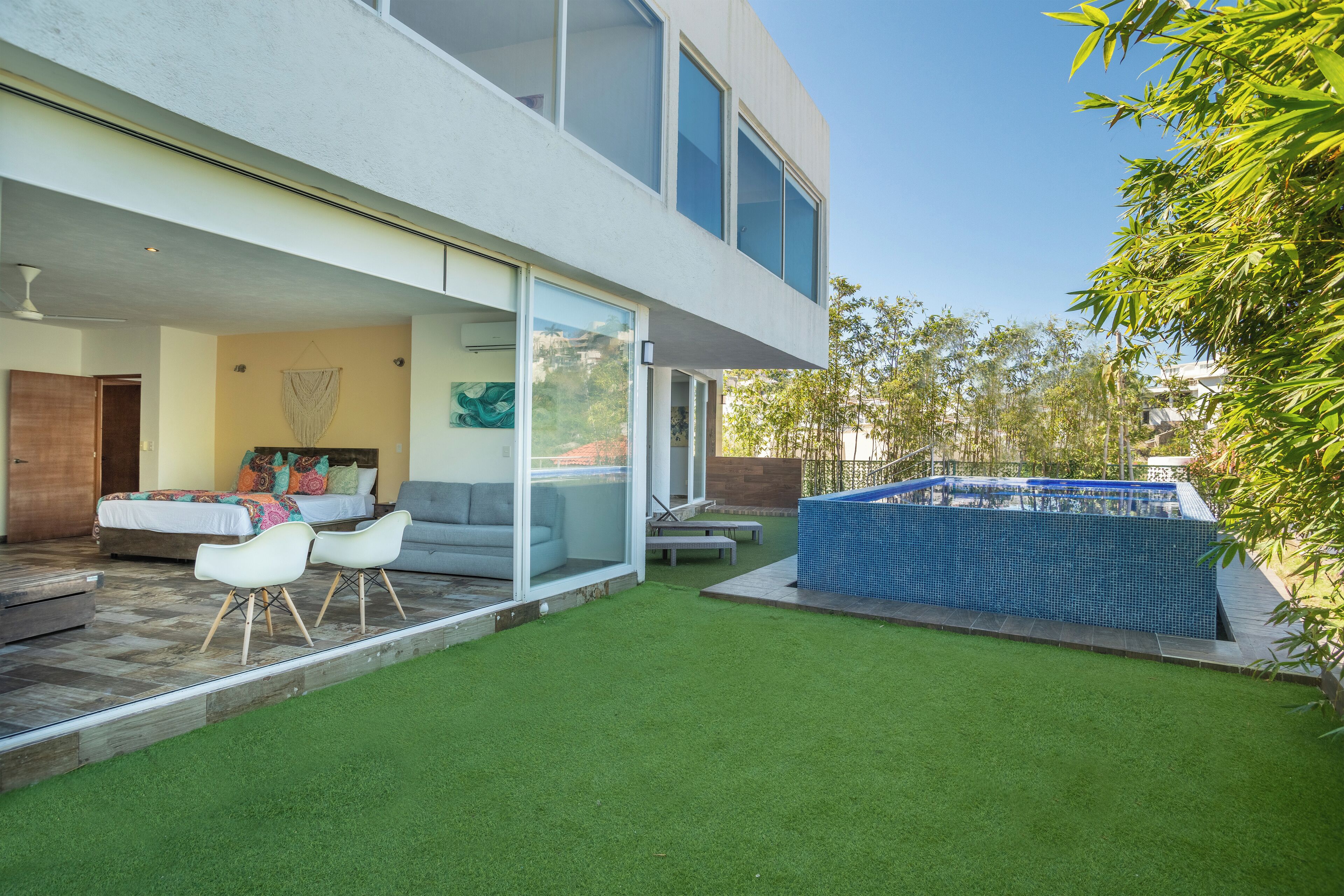 A modern house with a patio, a swimming pool, and a well-maintained lawn.