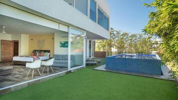 A modern house with a patio, a swimming pool, and a well-maintained lawn.