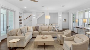 Un salon spacieux avec un grand canapé d’angle beige, une table basse et un lustre.