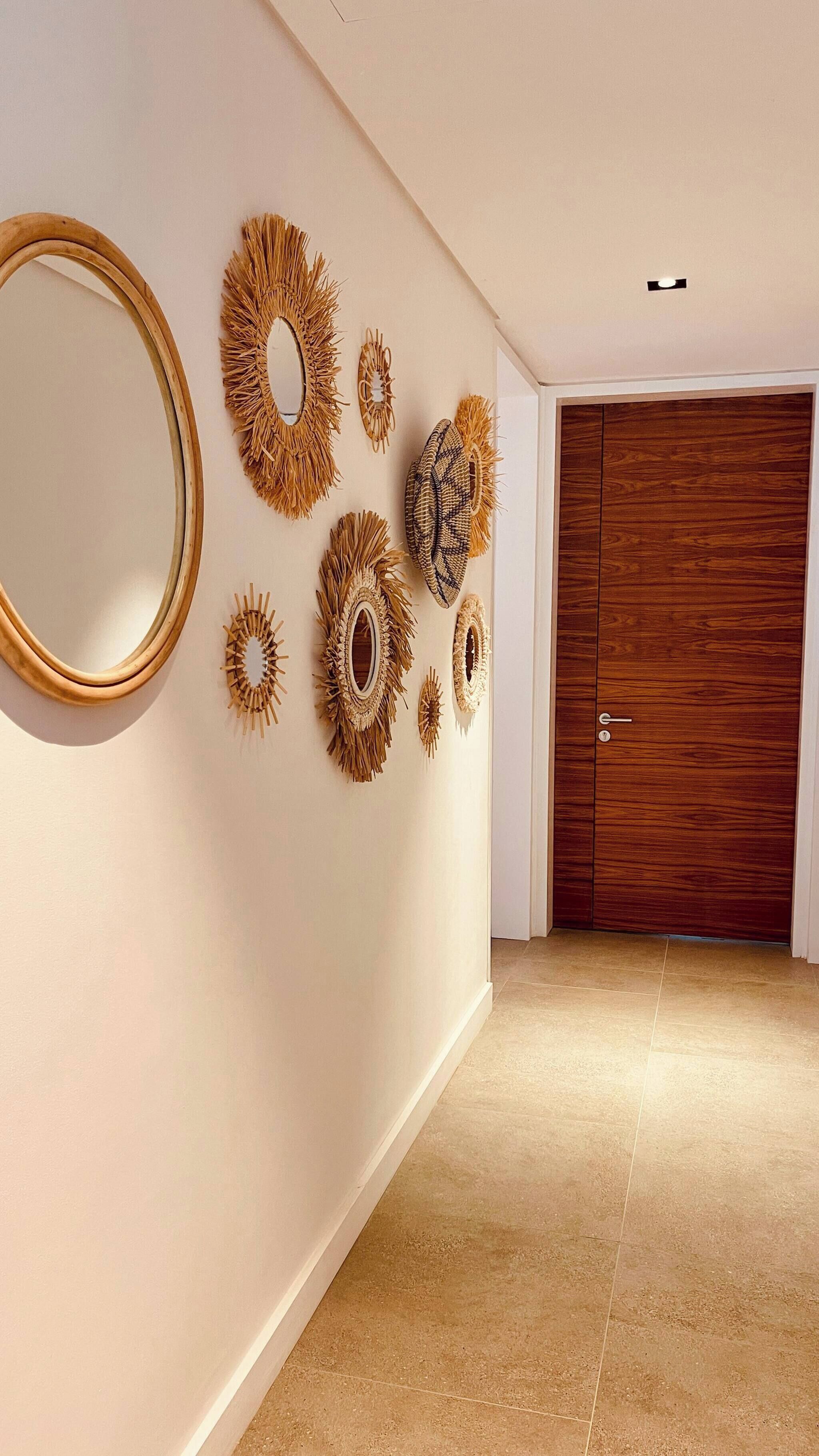 Un couloir avec une porte en bois, un miroir et des objets décoratifs fixés au mur.