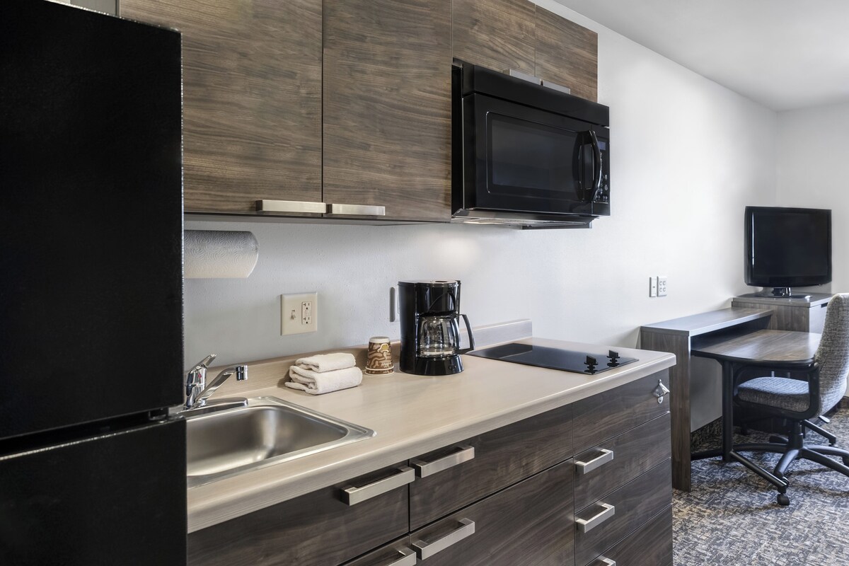 A modern kitchen with a stainless steel sink, a coffee maker, and wooden cabinets.