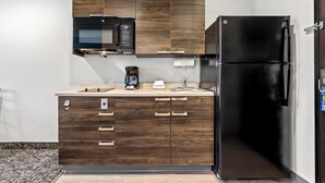 Una cocina moderna con armarios de madera, un refrigerador negro, un microondas y una cafetera.