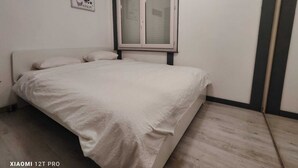 Un dormitorio con cama, ventana e imagen colgada en la pared.