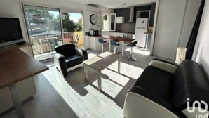 Un apartamento moderno con sala de estar, comedor, kitchenette y balcón.