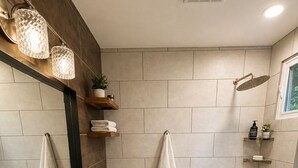 Une salle de bain moderne avec un grand miroir, deux lavabos, des toilettes et un espace douche.