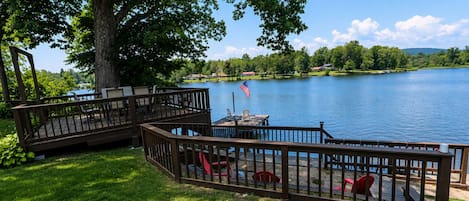 A lakeside deck with outdoor furniture and a flag.