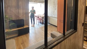 A modern interior with a wooden floor, a dining area with chairs and a table, and a person walking through a doorway. - Apartment with sea view, at the foot of the beach, ideal for a couple with 2 children (Saint-Cyprien)