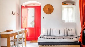 A room with a red door, a bed with patterned pillows, a wooden table, and a basket. - Casa Keller con Terrazza by Wonderful Italy (Noto)