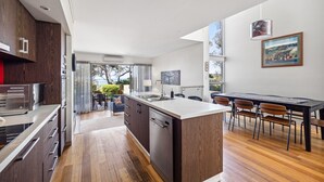Une cuisine moderne dotée d’un îlot central, d’un plancher en bois et d’un coin repas avec des chaises et une table.