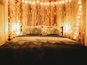 Un lit avec une tête de lit en bois et des guirlandes lumineuses.