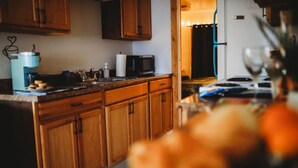 A kitchen with wooden cabinets, a microwave, and a coffee maker. - Raven's Perch Cabin B Peaceful Getaway-Aurora-AlaskanCabin (Fairbanks)