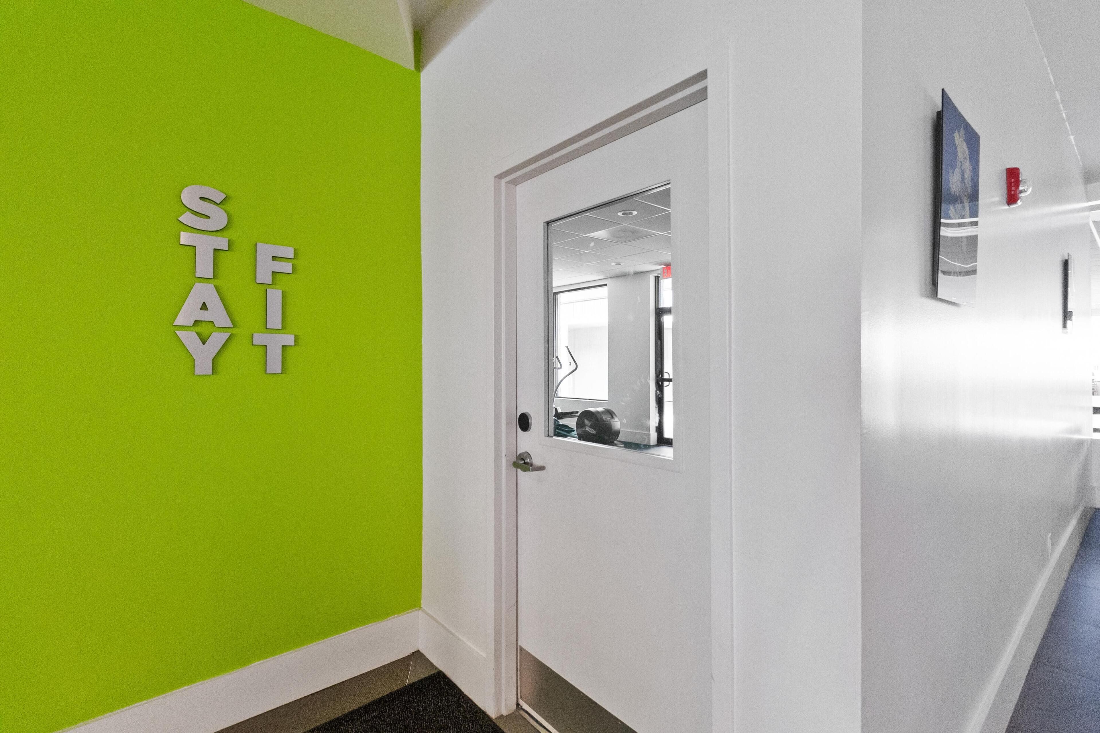 Un pasillo con una pared verde y una puerta blanca.