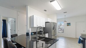A modern kitchen with a central island, stainless steel appliances, and white cabinetry. - 5/3 Pool home located in Sunset Ridge Community! (Davenport)