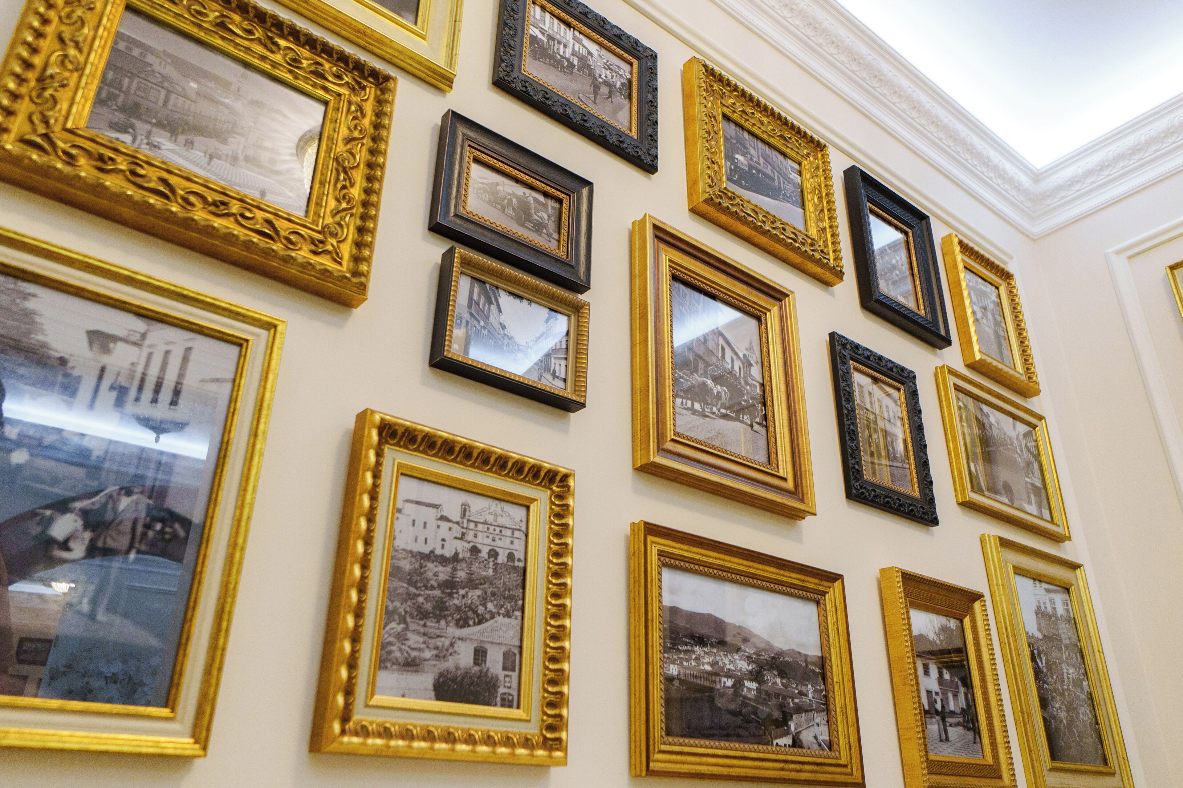 Een muur met meerdere ingelijste foto's in gouden en zwarte lijsten.