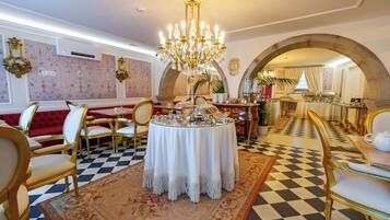 A dining area with a checkered floor, a round table with a white tablecloth, and gold chairs.