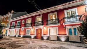 Un edificio histórico con calle adoquinada, puerta de madera y balcón con barandilla de hierro forjado.