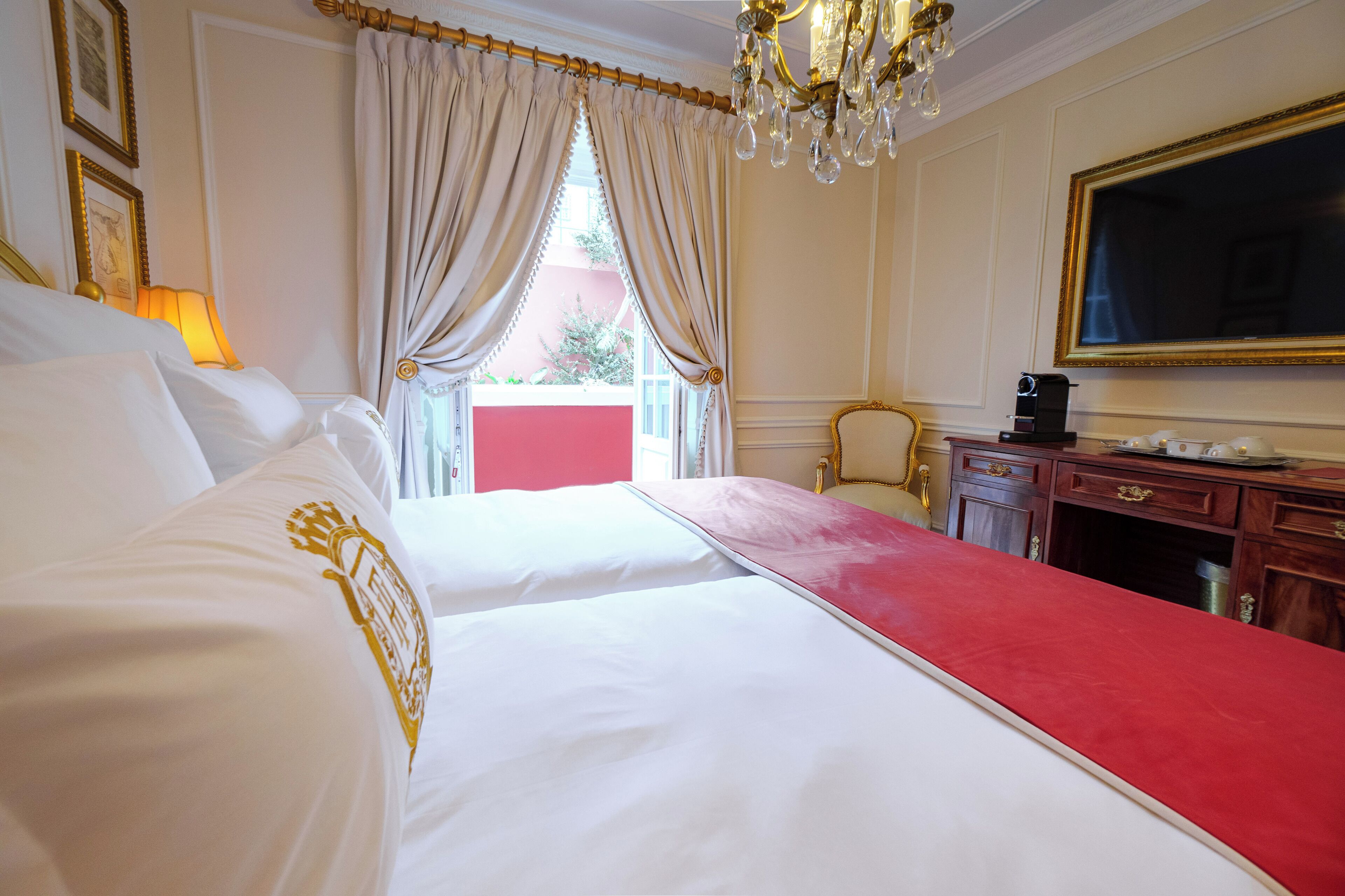 A hotel room with two beds, a desk, a chair, and a large mirror.