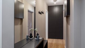 A modern hallway with a dark wooden floor, a black bench, and a wall-mounted light fixture. - Urban 1BR Loft Residences - Modern Comfort in Bucharest Center (Bucharest)