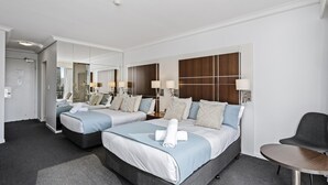 A hotel room with two beds, a desk, and a chair.