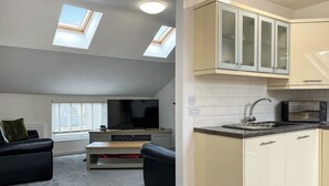 A modern apartment with a living room, a kitchen, and a small balcony.