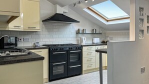 A modern kitchen with a skylight, white tiled backsplash, and a black stove.