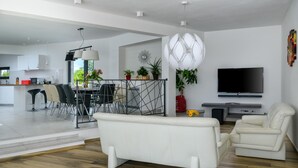 Un salon moderne comprenant un canapé, des fauteuils, un coin repas et un téléviseur.