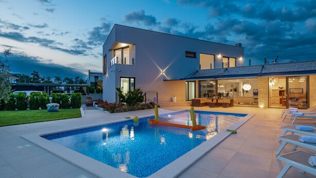 Une maison moderne à deux étages, dotée d’une piscine, d’un espace extérieur aménagé et d’un jardin bien entretenu.